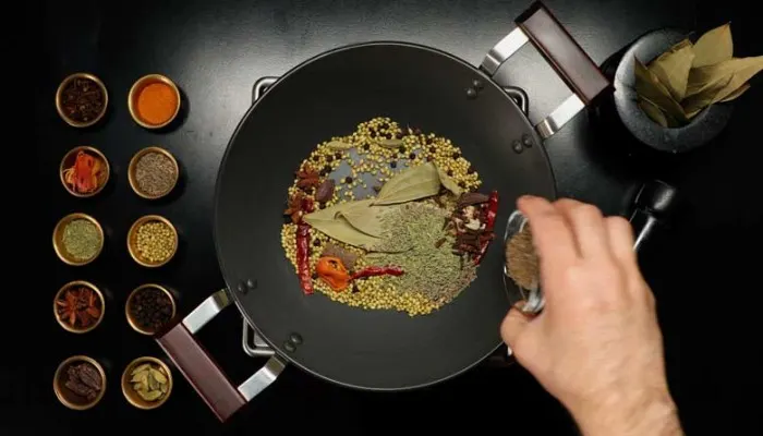 Dry roasting whole spices in an iron kadai for homemade Hyderabadi biryani masala powder.