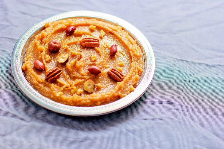 A warm bowl of eggless and milk-free sooji halwa garnished with chopped almonds A warm bowl of eggless and milk-free sooji halwa garnished with chopped almonds