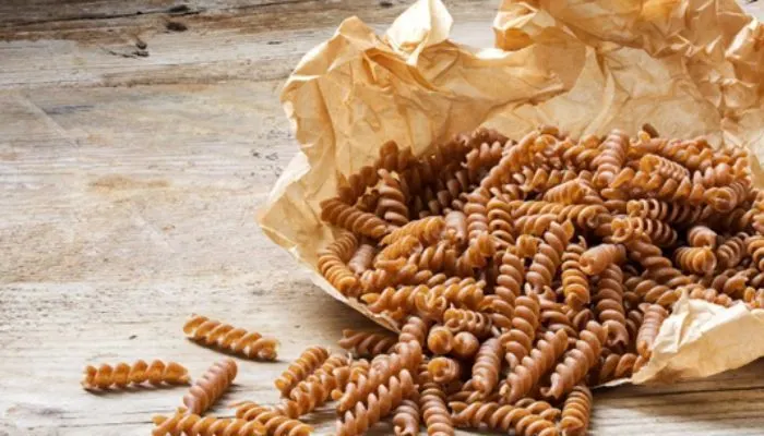 A delicious, healthy bowl of wholegrain pasta garnished with fresh herbs, representing a fibre-rich meal.