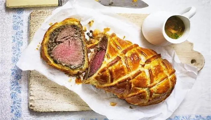 Golden brown, sliced Beef Wellington served with buttered greens