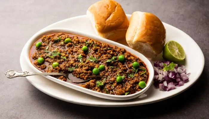 A hearty serving of beef keema curry topped with fresh peas and spinach in a skillet. A hearty serving of beef keema curry topped with fresh peas and spinach in a skillet.