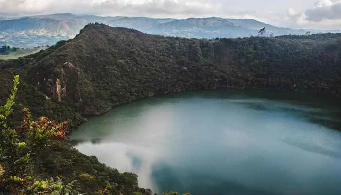 Lago Guatavita in Colombia, surrounded by lush green mountains, famously associated with the legend of El Dorado and gold offerings. Lago Guatavita in Colombia, surrounded by lush green mountains, famously associated with the legend of El Dorado and gold offerings.